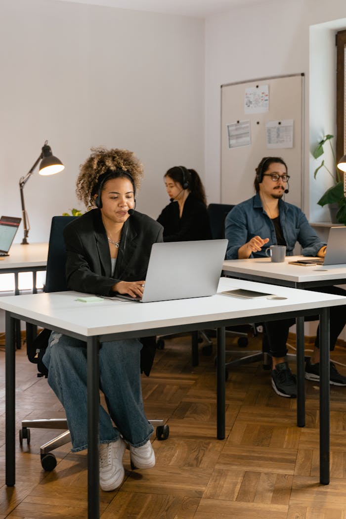 Diverse team of customer service agents working at desks in a modern office setting.